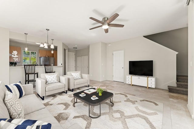 tiled living room featuring ceiling fan with notable chandelier