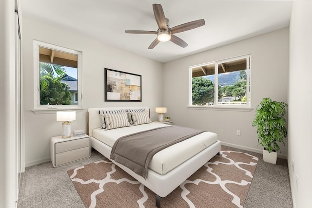 bedroom featuring light carpet, multiple windows, and ceiling fan