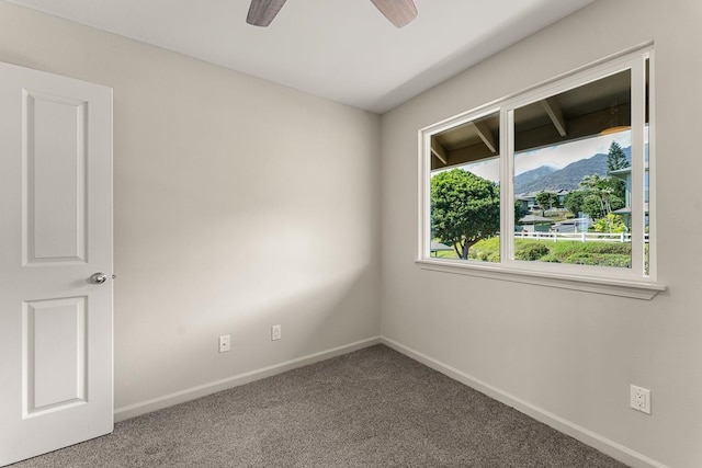 carpeted empty room featuring a mountain view and ceiling fan