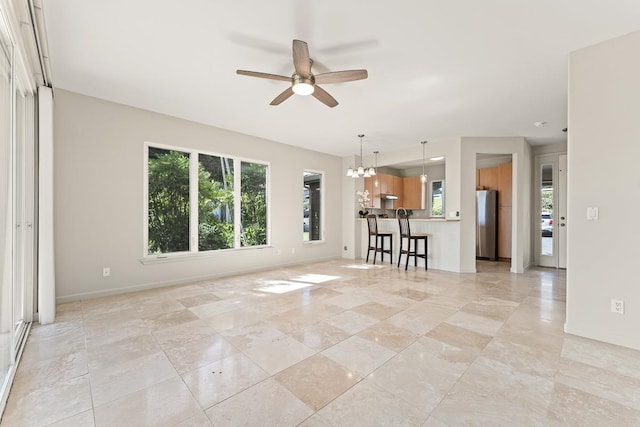 unfurnished living room with ceiling fan with notable chandelier