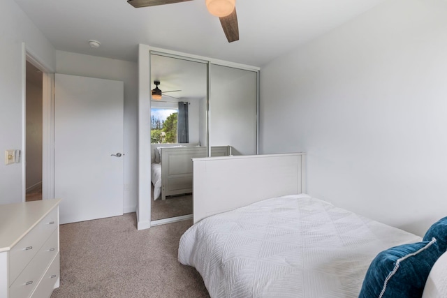 bedroom featuring light colored carpet, ceiling fan, and a closet