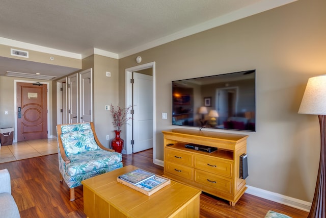 living room with ornamental molding, dark wood-type flooring, and a textured ceiling