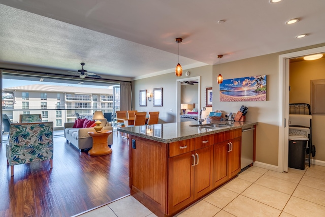 kitchen featuring sink, stone countertops, kitchen peninsula, hanging light fixtures, and light hardwood / wood-style flooring