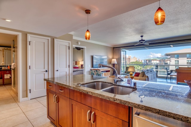 kitchen featuring light tile patterned floors, light stone countertops, sink, and pendant lighting