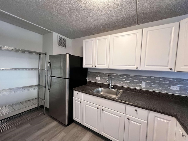 kitchen featuring stainless steel fridge, backsplash, dark wood-type flooring, sink, and white cabinetry