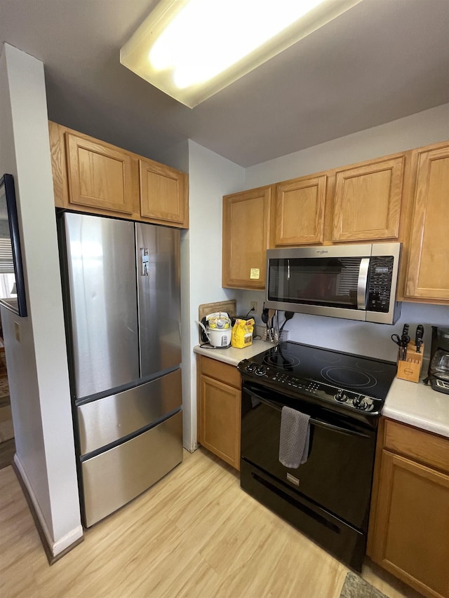 kitchen featuring appliances with stainless steel finishes, light wood-type flooring, and light countertops
