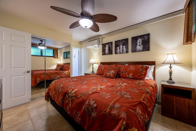 bedroom featuring ceiling fan, light tile patterned floors, an AC wall unit, and a closet