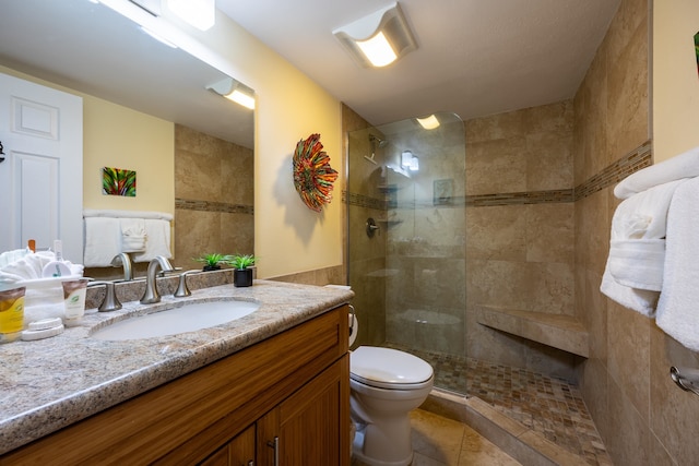 bathroom featuring tiled shower, tile patterned floors, vanity, and toilet