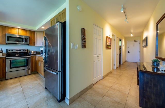 kitchen with appliances with stainless steel finishes, rail lighting, and light tile patterned flooring