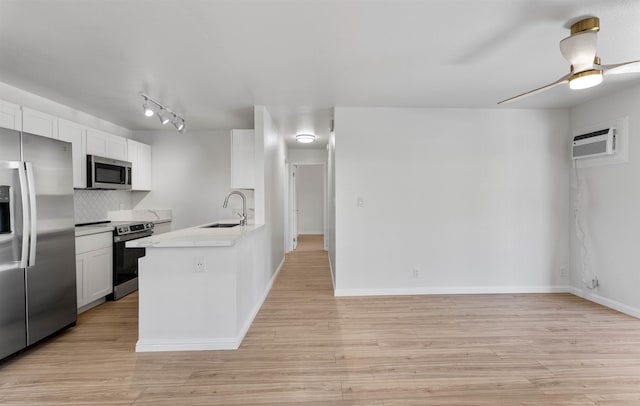 kitchen featuring stainless steel appliances, a sink, white cabinetry, light countertops, and a wall mounted AC