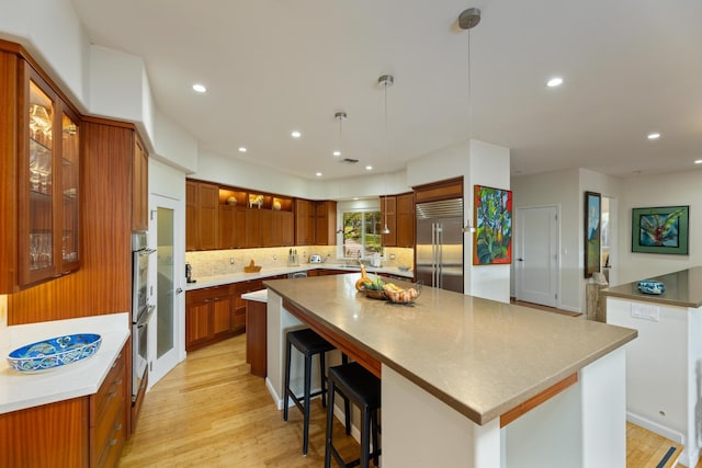 kitchen with stainless steel appliances, tasteful backsplash, a kitchen island, and decorative light fixtures