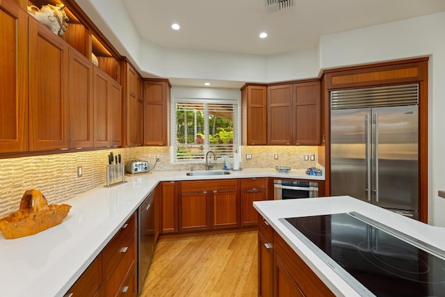 kitchen featuring backsplash, appliances with stainless steel finishes, sink, and light wood-type flooring