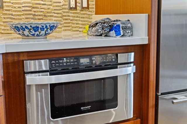 room details with stainless steel fridge, wall oven, and decorative backsplash