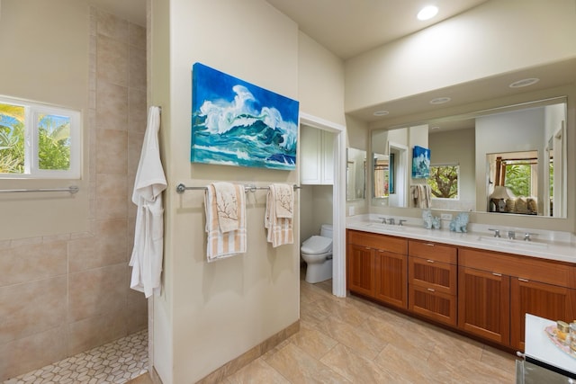 bathroom with vanity, toilet, and tiled shower