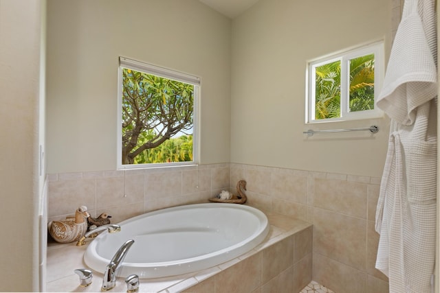 bathroom featuring tiled tub and a wealth of natural light