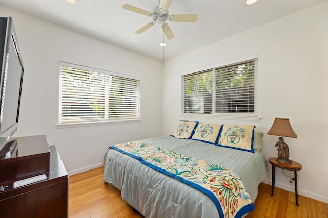 bedroom featuring ceiling fan, light hardwood / wood-style floors, and multiple windows