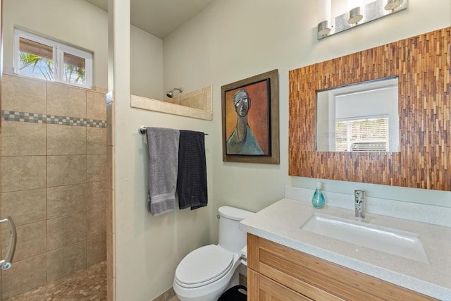 bathroom featuring vanity, plenty of natural light, tiled shower, and toilet