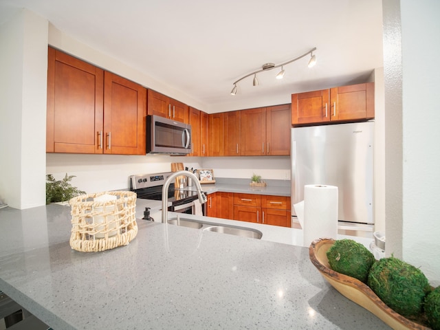 2747 S Kihei Rd Unit C004, Kihei, HI 96753 - kitchen featuring appliances with stainless steel finishes, light stone counters, a sink, brown cabinets, and a peninsula