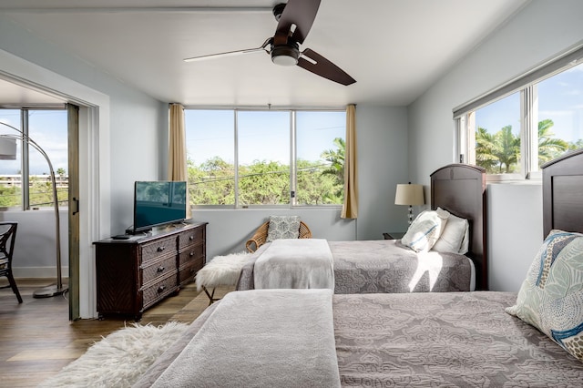 bedroom featuring ceiling fan, multiple windows, and hardwood / wood-style flooring