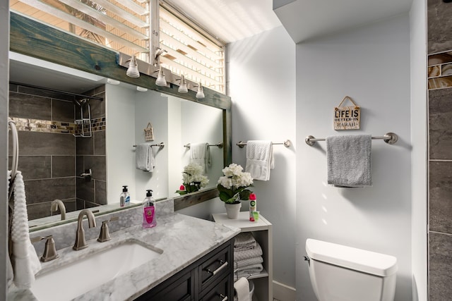 bathroom featuring a tile shower, vanity, and toilet