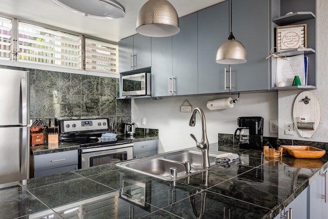 kitchen with sink, decorative light fixtures, appliances with stainless steel finishes, and tasteful backsplash