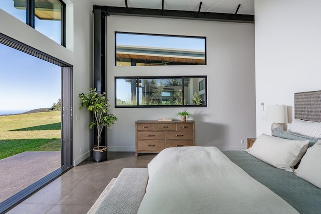 bedroom with a high ceiling, access to outside, and concrete floors