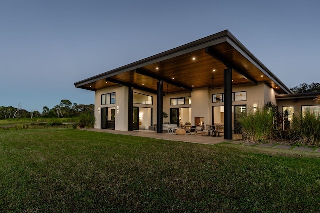back house at dusk with a yard and a patio area