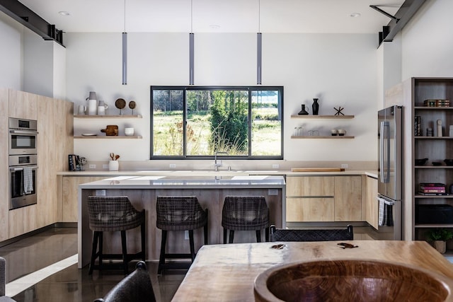 kitchen with stainless steel appliances, hanging light fixtures, and light brown cabinets