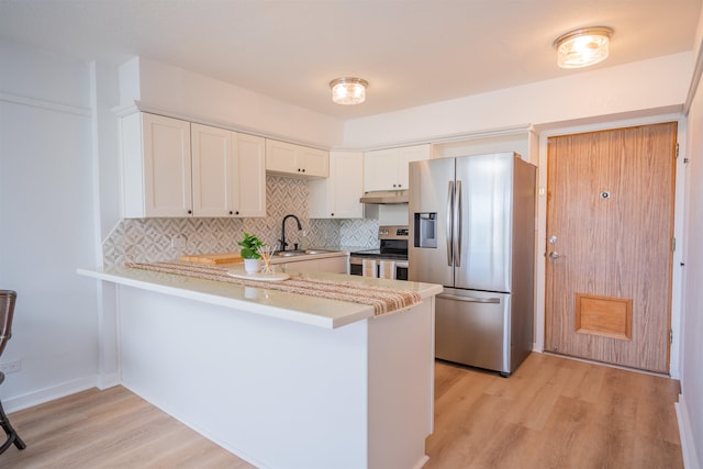 kitchen with light hardwood / wood-style floors, stainless steel appliances, sink, kitchen peninsula, and white cabinets