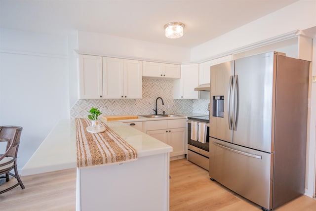 kitchen featuring light wood-type flooring, appliances with stainless steel finishes, decorative backsplash, and sink