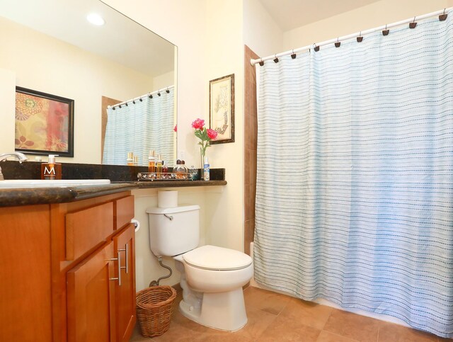 bathroom with tile patterned flooring, walk in shower, toilet, and vanity