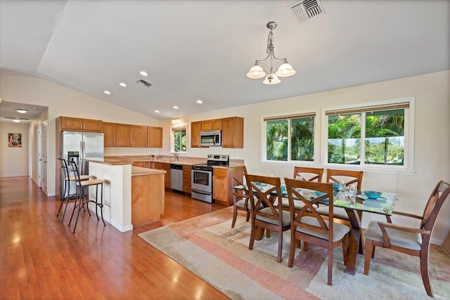 dining area with an inviting chandelier, lofted ceiling, sink, and light hardwood / wood-style floors