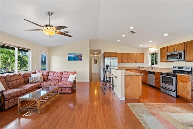 kitchen with a kitchen island, appliances with stainless steel finishes, a healthy amount of sunlight, and a kitchen breakfast bar