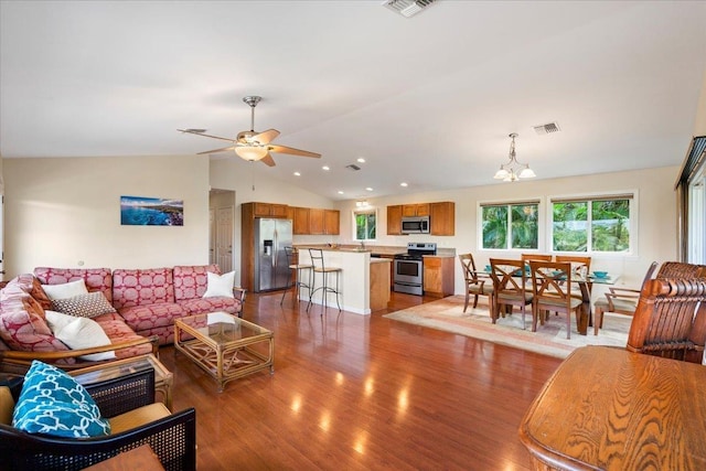 living room with vaulted ceiling, wood-type flooring, and ceiling fan with notable chandelier