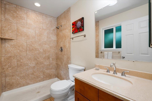 bathroom with vanity, tiled shower, and toilet