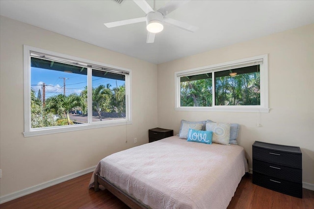 bedroom with multiple windows, dark wood-type flooring, and ceiling fan