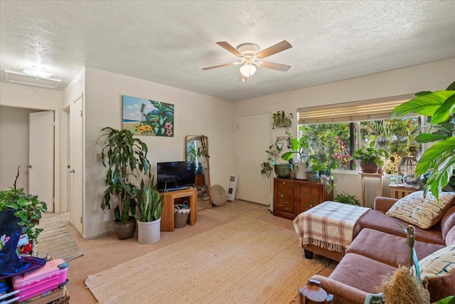 living room with light carpet, ceiling fan, and a textured ceiling