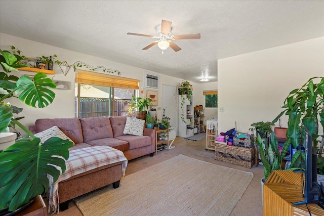 living room featuring ceiling fan, a wall mounted AC, light colored carpet, and a textured ceiling