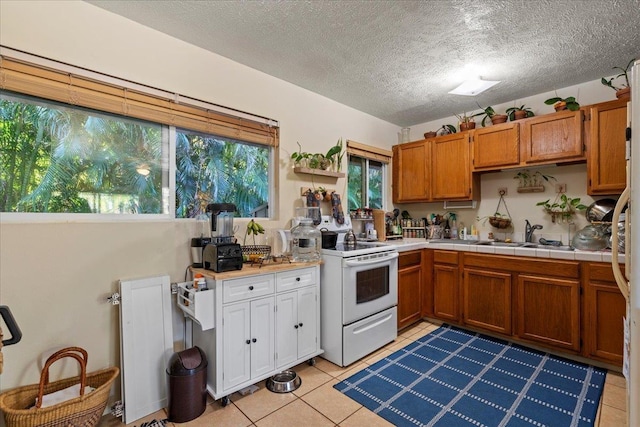 kitchen featuring white electric stove, light tile patterned flooring, sink, and tile counters