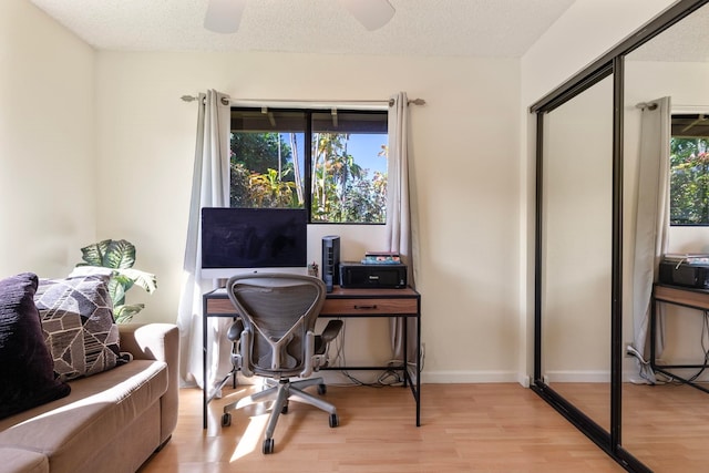 office space featuring a textured ceiling, baseboards, wood finished floors, and a healthy amount of sunlight