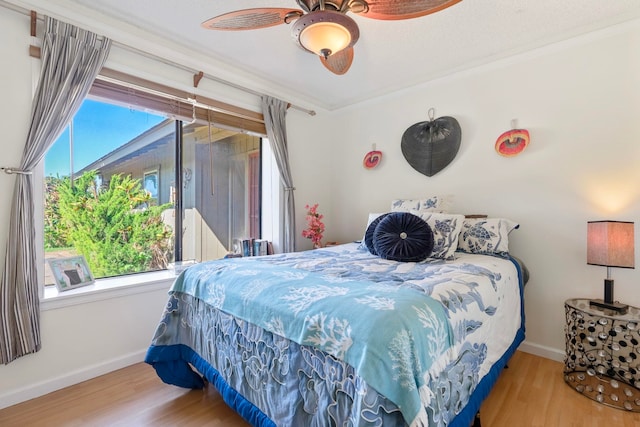 bedroom with ceiling fan, crown molding, wood finished floors, and baseboards