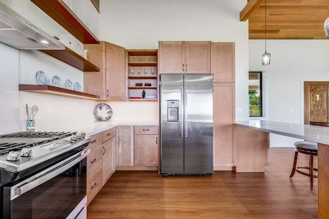 kitchen featuring hanging light fixtures, dark wood-type flooring, stainless steel appliances, a breakfast bar area, and a towering ceiling