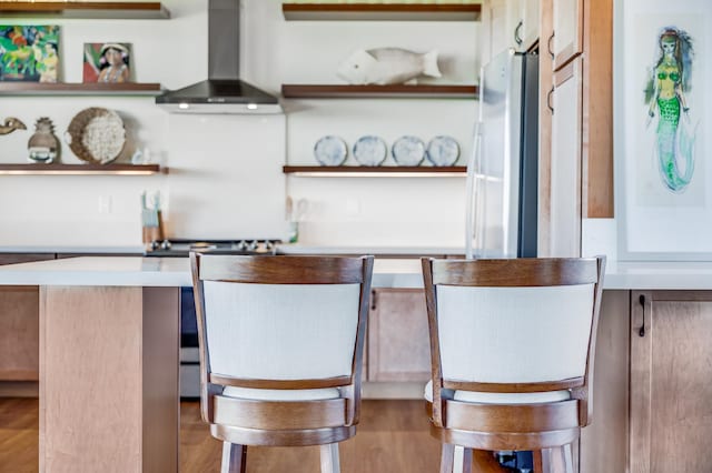 interior space with light wood-type flooring, range, wall chimney exhaust hood, and white refrigerator