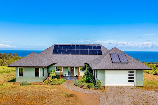 view of front facade with a garage, solar panels, and a water view