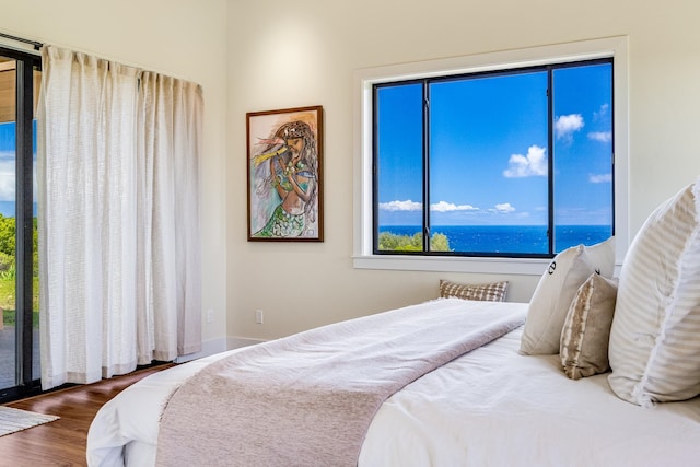 bedroom featuring wood-type flooring and a water view