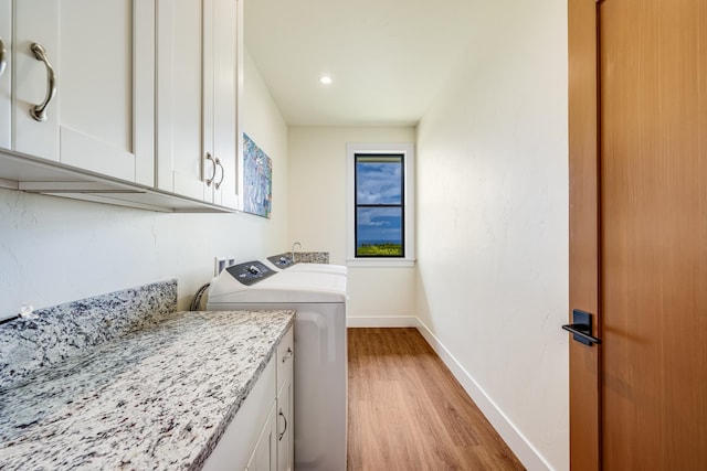 laundry area featuring cabinets, light wood-type flooring, and independent washer and dryer