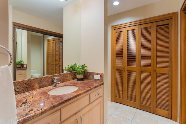 bathroom featuring toilet, tile flooring, and vanity