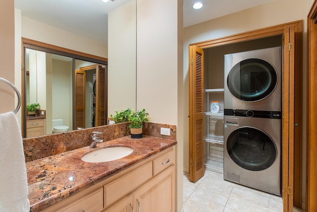 bathroom with toilet, stacked washer / dryer, vanity, and tile flooring