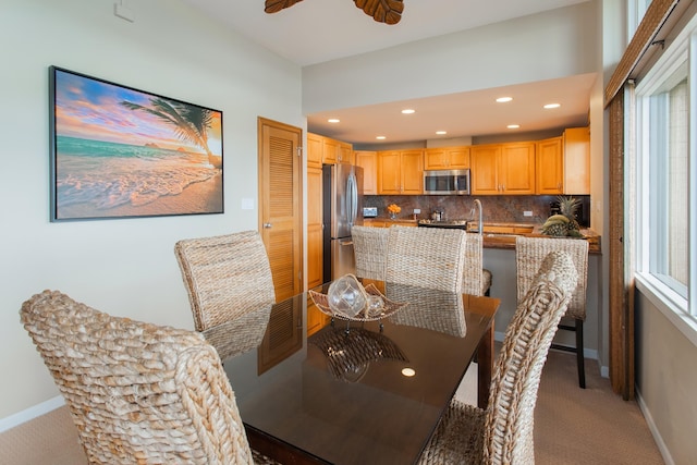 dining space featuring light carpet and ceiling fan