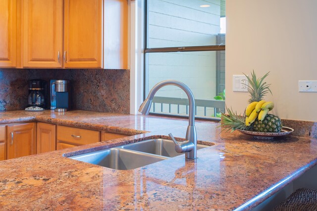 kitchen with light stone countertops, tasteful backsplash, and sink